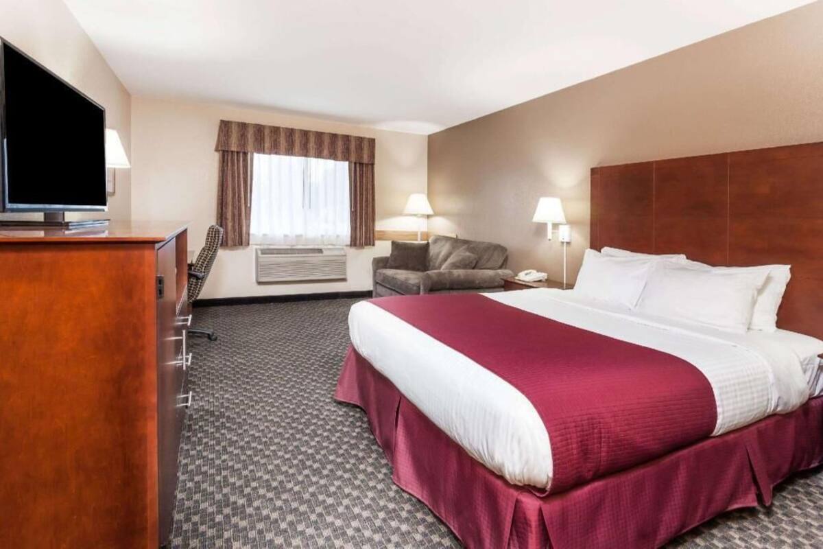 A hotel room with a bed, a desk, a television, a chair, and a window with curtains.