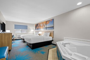 A hotel room with two beds, a large window, a painting, a bathtub, and a desk. - Days Inn by Wyndham Imlay City (Imlay City)