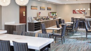 A hotel dining area with multiple tables and chairs, a buffet counter, and artwork on the walls. - Residence Inn By Marriott Minneapolis Downtown (Minneapolis)