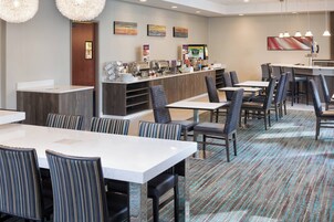 Un comedor de hotel con varias mesas y sillas, un mostrador de buffet y obras de arte en las paredes.