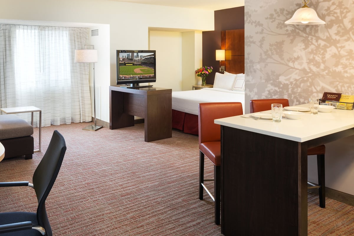 Une chambre d’hôtel comprenant un lit, un bureau, une télévision, un coin repas et un espace salon.