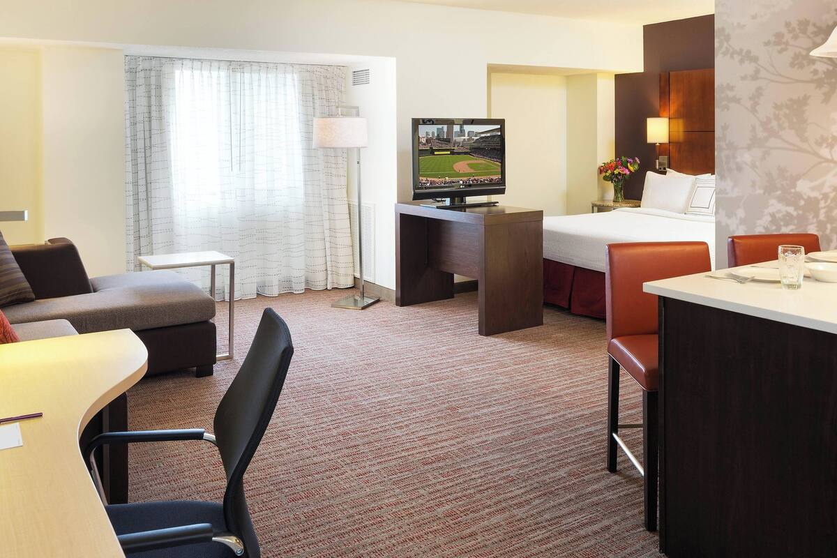Une chambre d’hôtel comprenant un lit, un bureau avec une télévision, une petite table, une chaise et un canapé.