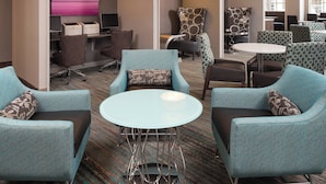 A modern hotel lobby with teal armchairs, a glass coffee table, and a reception area with a computer and printer. - Residence Inn By Marriott Minneapolis Downtown (Minneapolis)