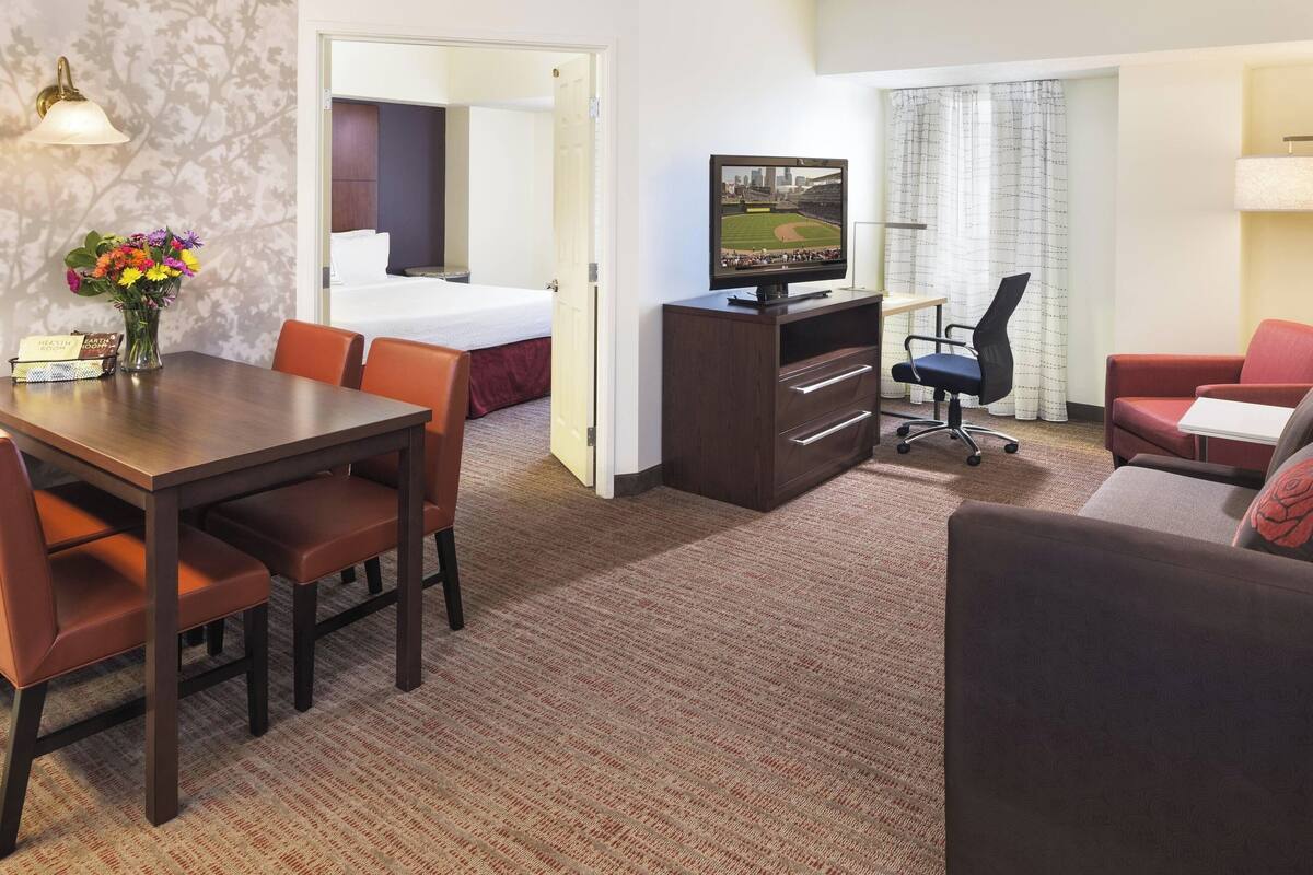 Une chambre d’hôtel comprenant un coin repas, une télévision, un canapé et un lit.