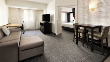 Habitación de hotel con sofá, escritorio con lámpara, televisión y cama.
