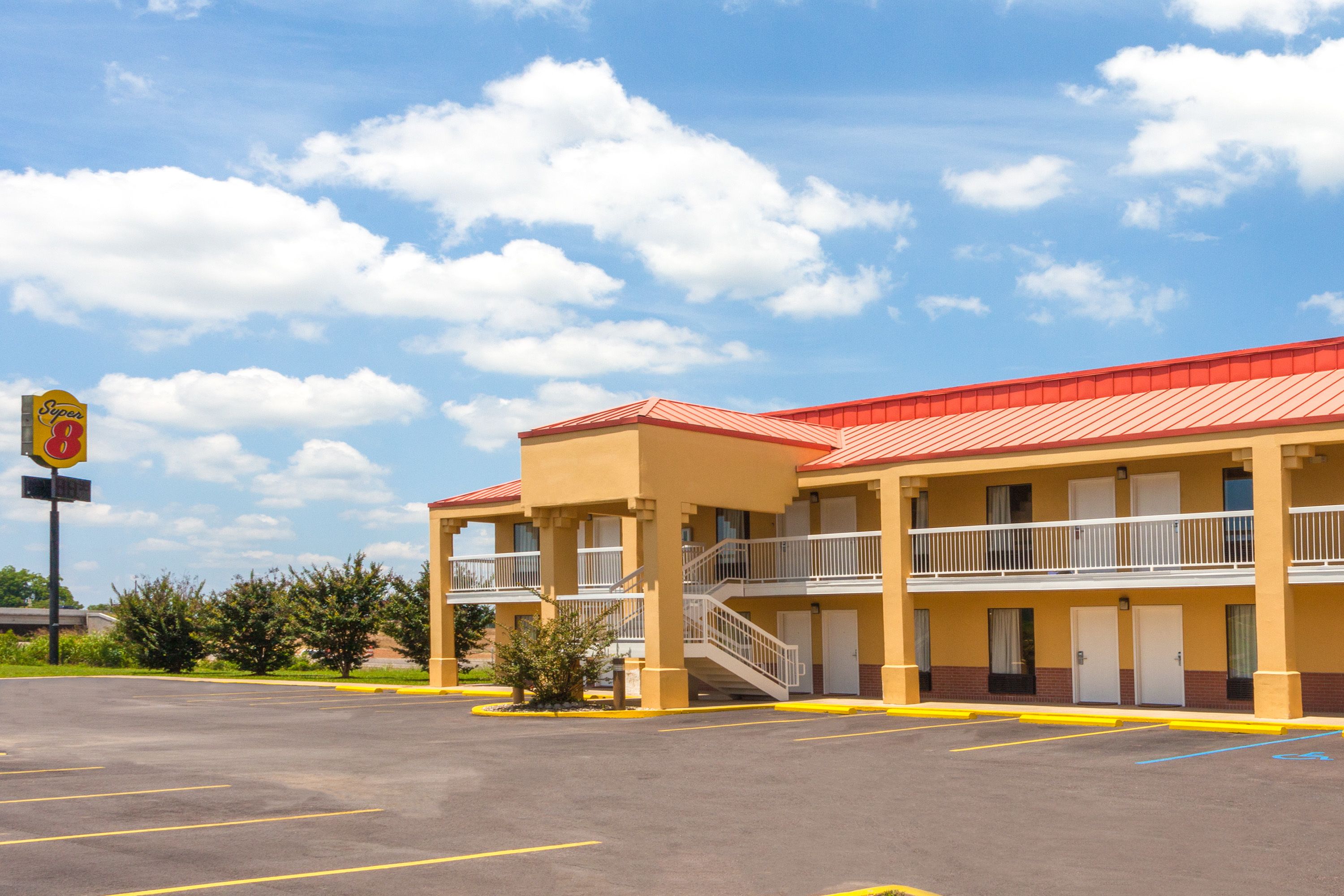 Un motel avec un toit rouge, de nombreux balcons et un parking.