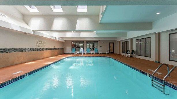 An indoor swimming pool with clear water, a tiled edge, and a lifeguard sign. - Hampton Inn Jefferson City at Capital Mall (Jefferson City)