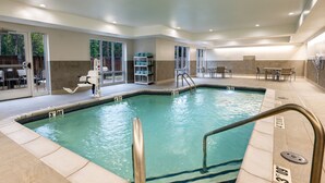 An indoor swimming pool with clear water, a diving board, and a seating area with tables and chairs. - Fairfield Inn & Suites by Marriott St. Louis Chesterfield (Chesterfield)