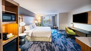 A hotel room with a bed, desk, TV, and a view of the outdoors. - Fairfield Inn & Suites by Marriott St. Louis Chesterfield (Chesterfield)