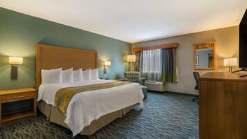 A hotel room with a large bed, bedside tables, a desk, a chair, and a window with curtains.
