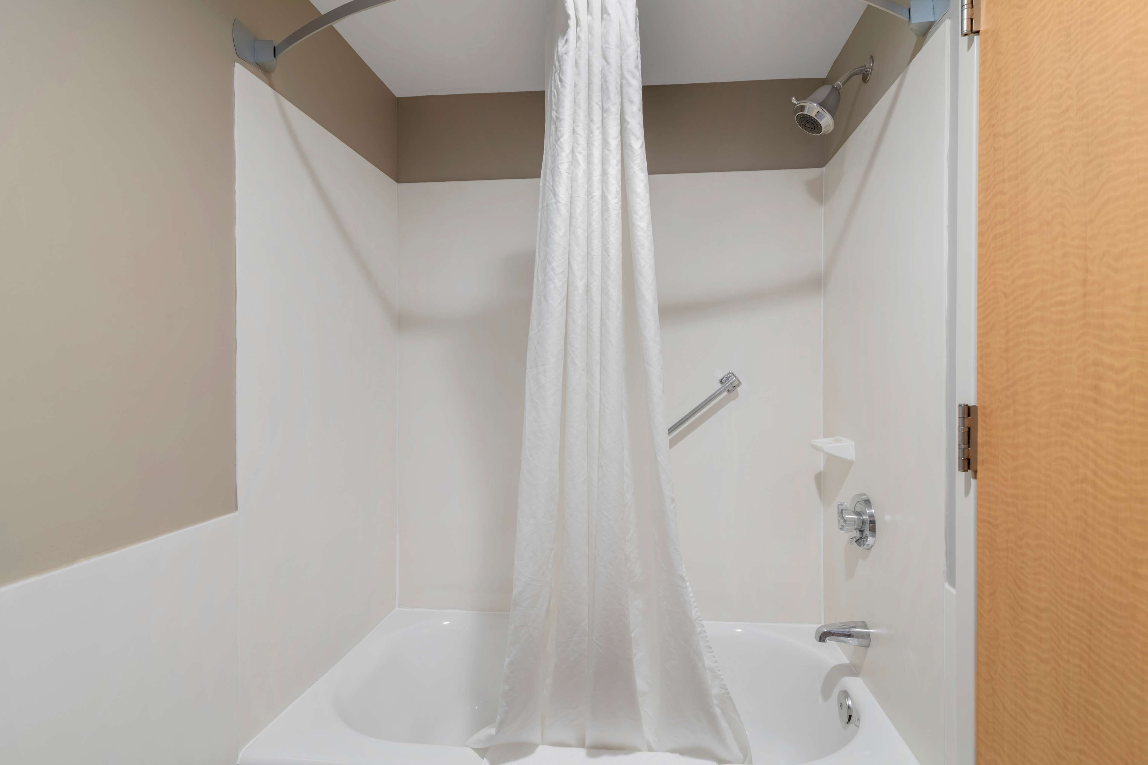 A bathroom with a bathtub, a shower curtain, and a showerhead.