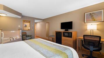 A hotel room with a bed, a desk, a chair, a television, a lamp, a mirror, and a bathroom with a bathtub and sink.