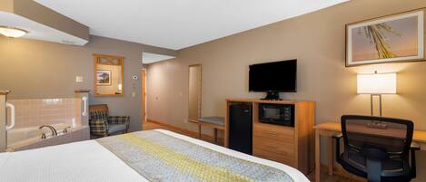 A hotel room with a bed, a desk, a chair, a television, a lamp, a mirror, and a bathroom with a bathtub and sink.