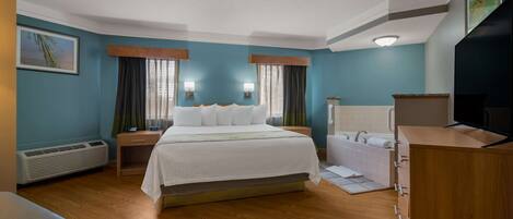 Habitación de hotel con una cama grande, un escritorio, un tocador con espejo y un televisor.