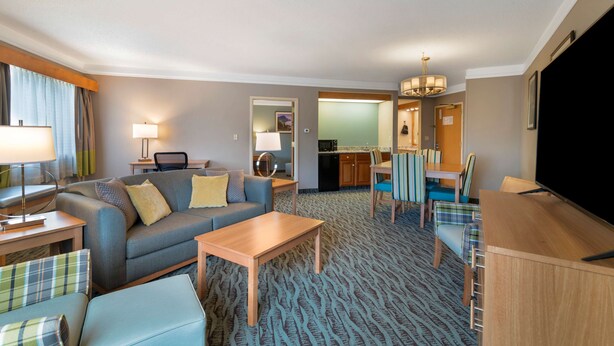 A hotel room with a living area, a dining table, a sofa, a coffee table, and a TV.
