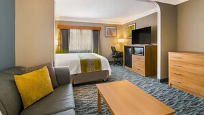 A hotel room with a bed, a sofa, a TV, a desk, and a dresser.
