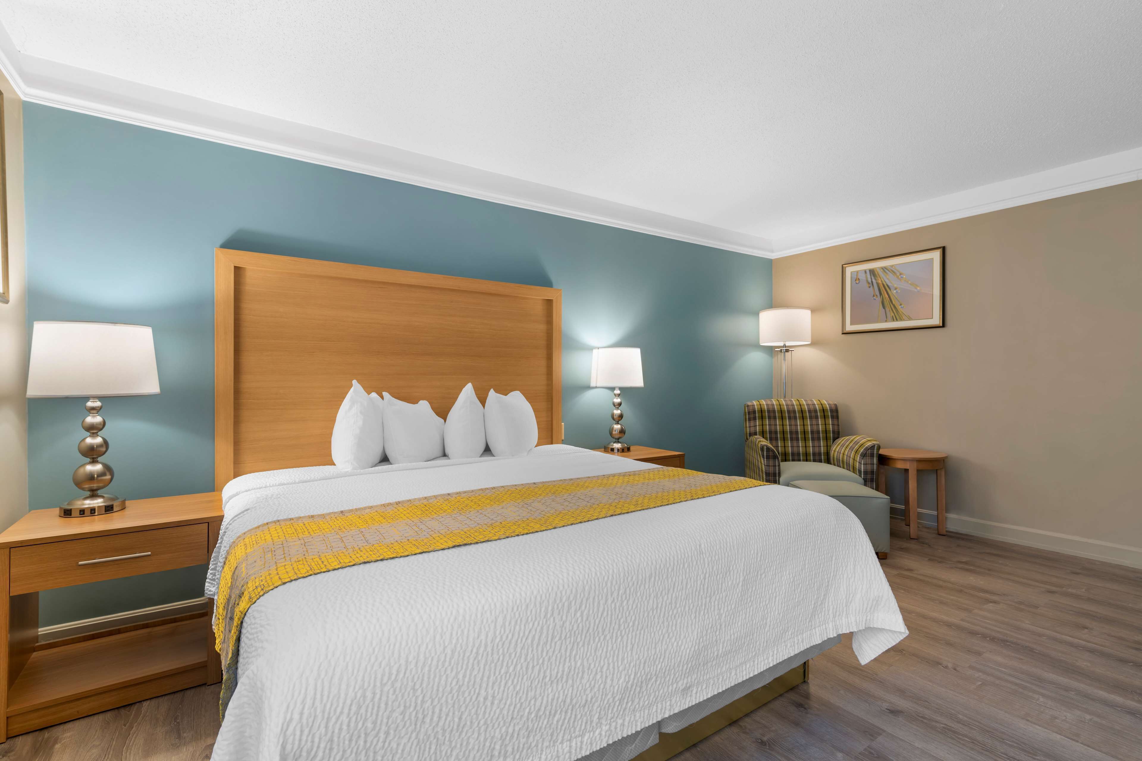 A neatly arranged hotel room with a large bed, two bedside tables, a chair, and a small table.