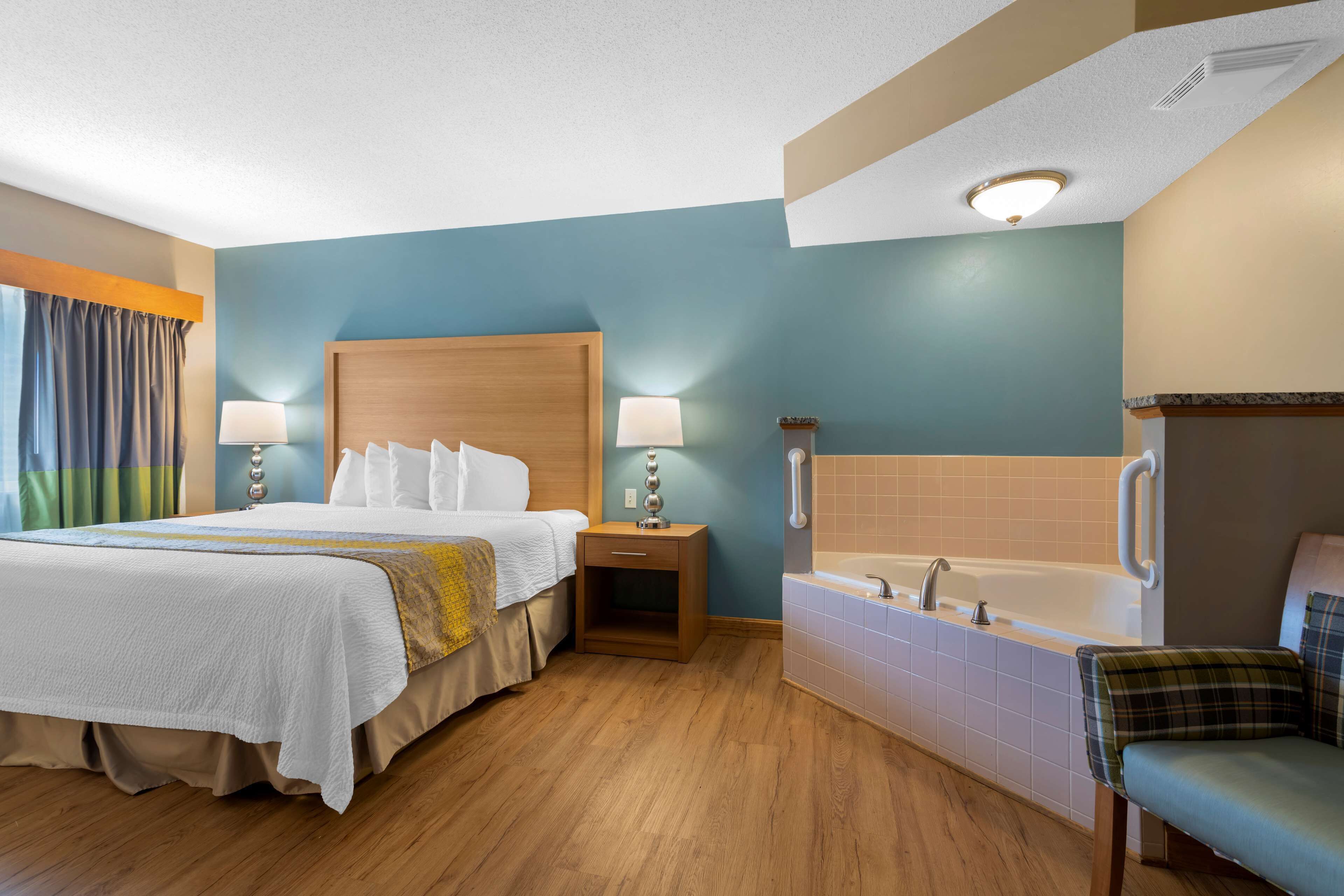 Une chambre d’hôtel avec un grand lit, une salle de bain séparée avec une baignoire et un petit coin salon.