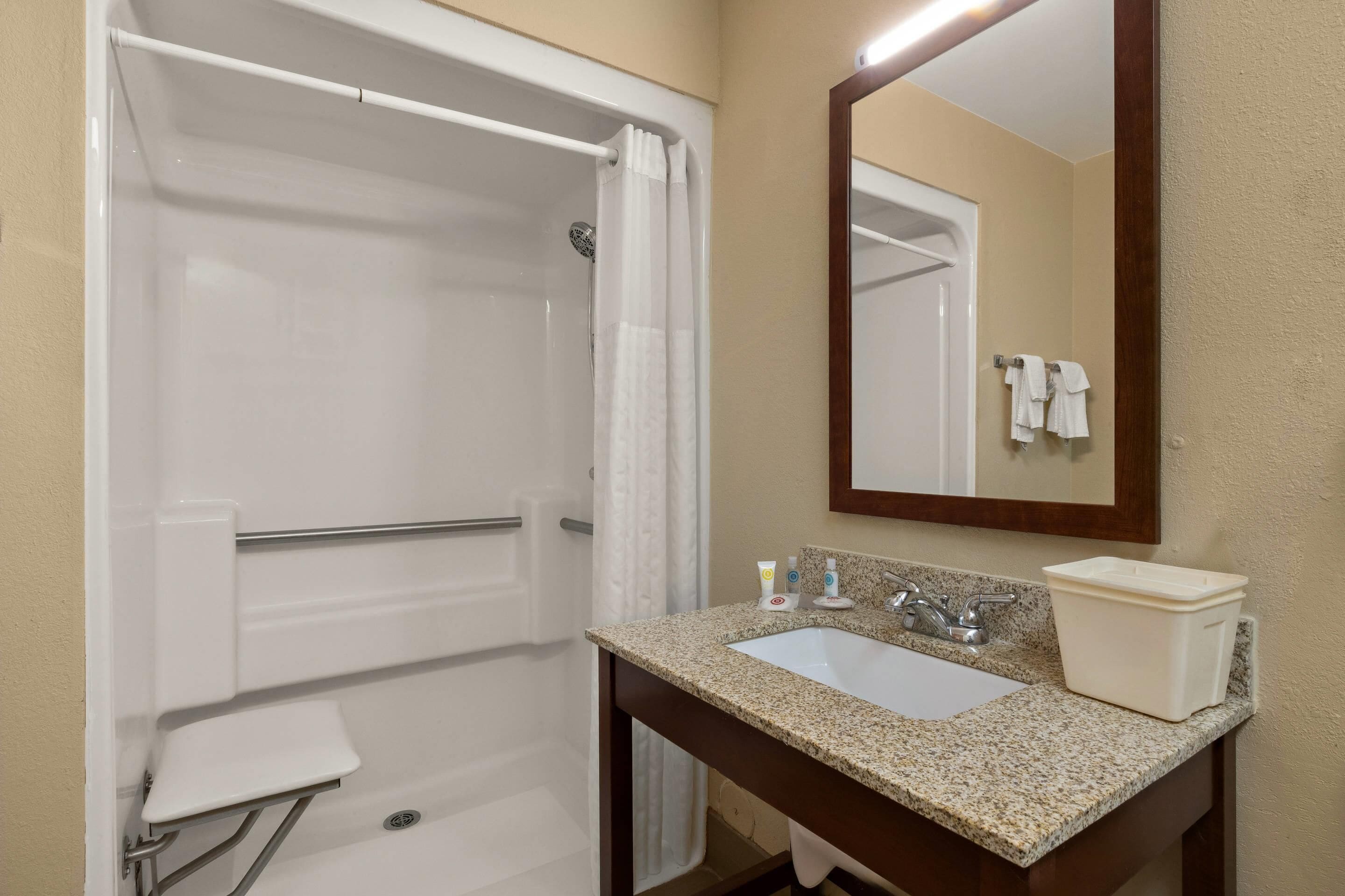 A bathroom with a shower, a sink, a mirror, and a towel rack.