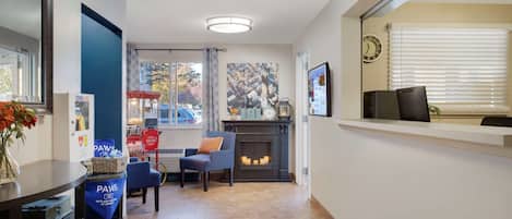 Un área de recepción con chimenea, un reloj y una ventana con persianas.