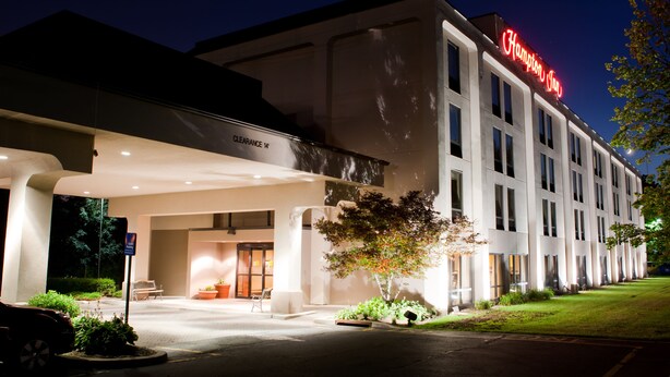 A hotel with a modern facade, a clear sign indicating a 14-foot clearance, and a well-lit entrance. - Hampton Inn Ridgefield Park (Ridgefield Park)