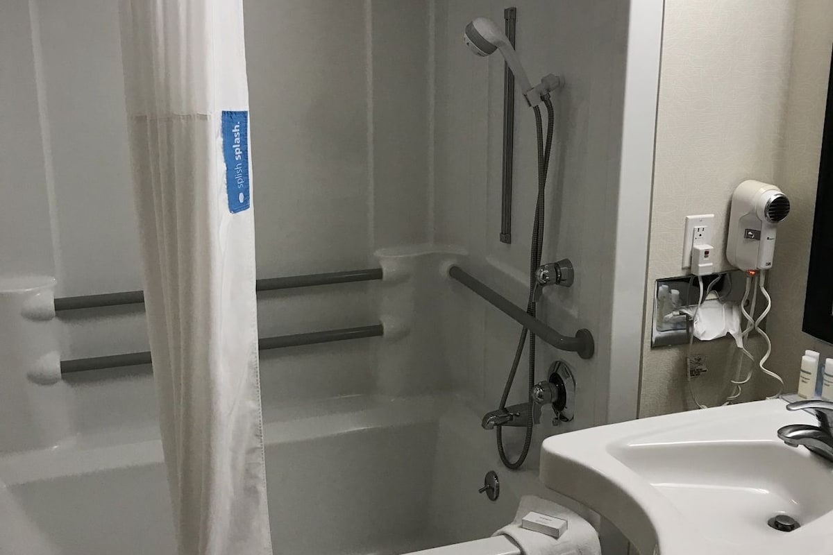 A bathroom with a shower, a sink, and a mirror.