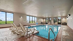 An indoor swimming pool with clear views through large windows, a pool lift, and lounge chairs. - Hampton Inn Ridgefield Park (Ridgefield Park)