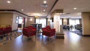 A hotel lobby with red chairs, a coffee table, and a large decorative sculpture. - Hampton Inn Ridgefield Park (Ridgefield Park)