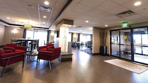A hotel lobby with red chairs, a dining area, and an exit sign. - Hampton Inn Ridgefield Park (Ridgefield Park)