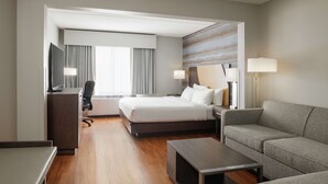 A modern hotel room with a large bed, a desk, a sofa, and a TV. - Hotel Trilogy Albany Airport, Tapestry Collection by Hilton (Latham)