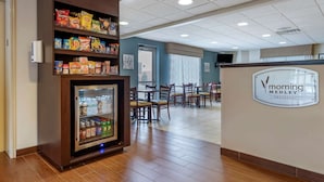 Un área de desayuno con un refrigerador lleno de aperitivos, una cafetera y un cartel que anuncia el desayuno Morning Medley.