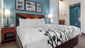 Una habitación de hotel con una cama grande, lámparas de noche, una mesita de noche y una pared con cuadros.