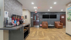A reception area with a counter, chairs, and a wall-mounted TV. - Extended Stay America Suites Charlotte Pineville Park Rd (Pineville)