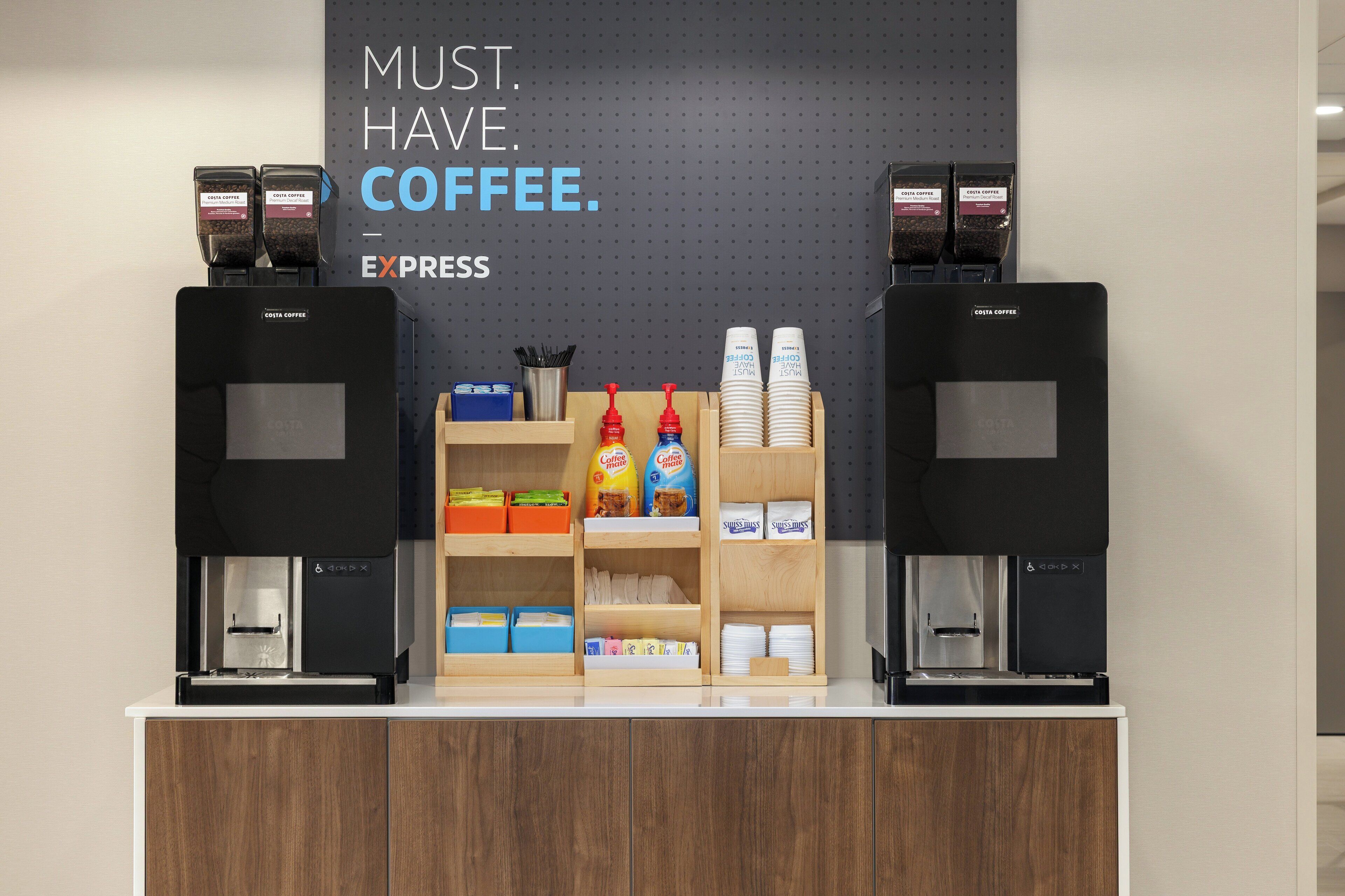 A coffee station with two espresso machines, labeled Costa Coffee, and a variety of coffee pods and cups.