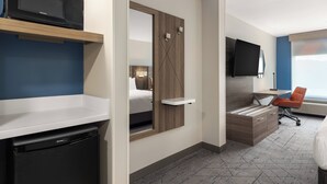 A hotel room with a bed, a desk, a chair, a TV, and a microwave. - Holiday Inn Express Fayetteville – Fort Bragg by IHG (Fayetteville)