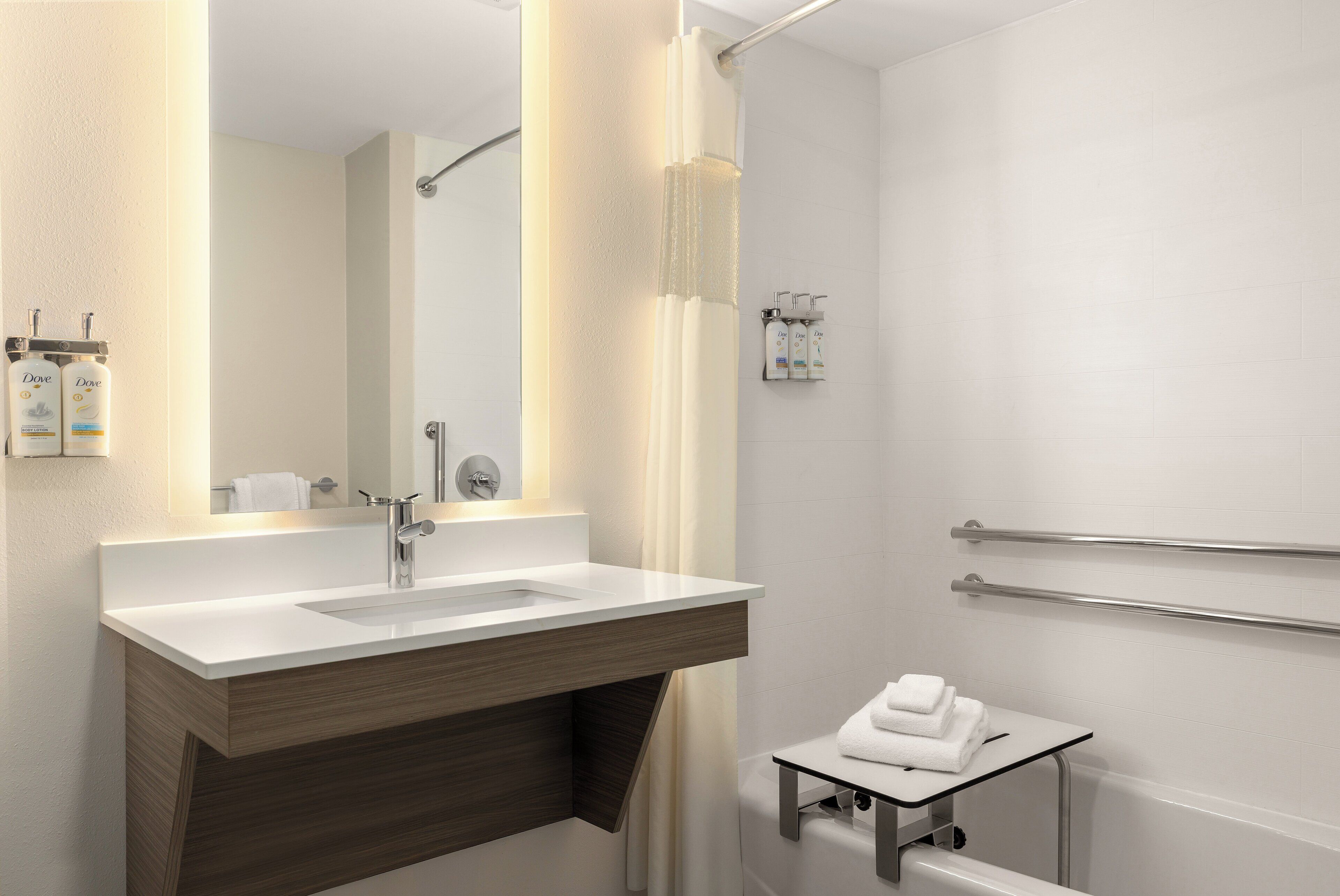 A modern bathroom with a sink, mirror, shower, and towel rack.