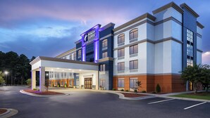 A Holiday Inn Express hotel with a modern facade, a covered entrance, and landscaped surroundings. - Holiday Inn Express Fayetteville – Fort Bragg by IHG (Fayetteville)