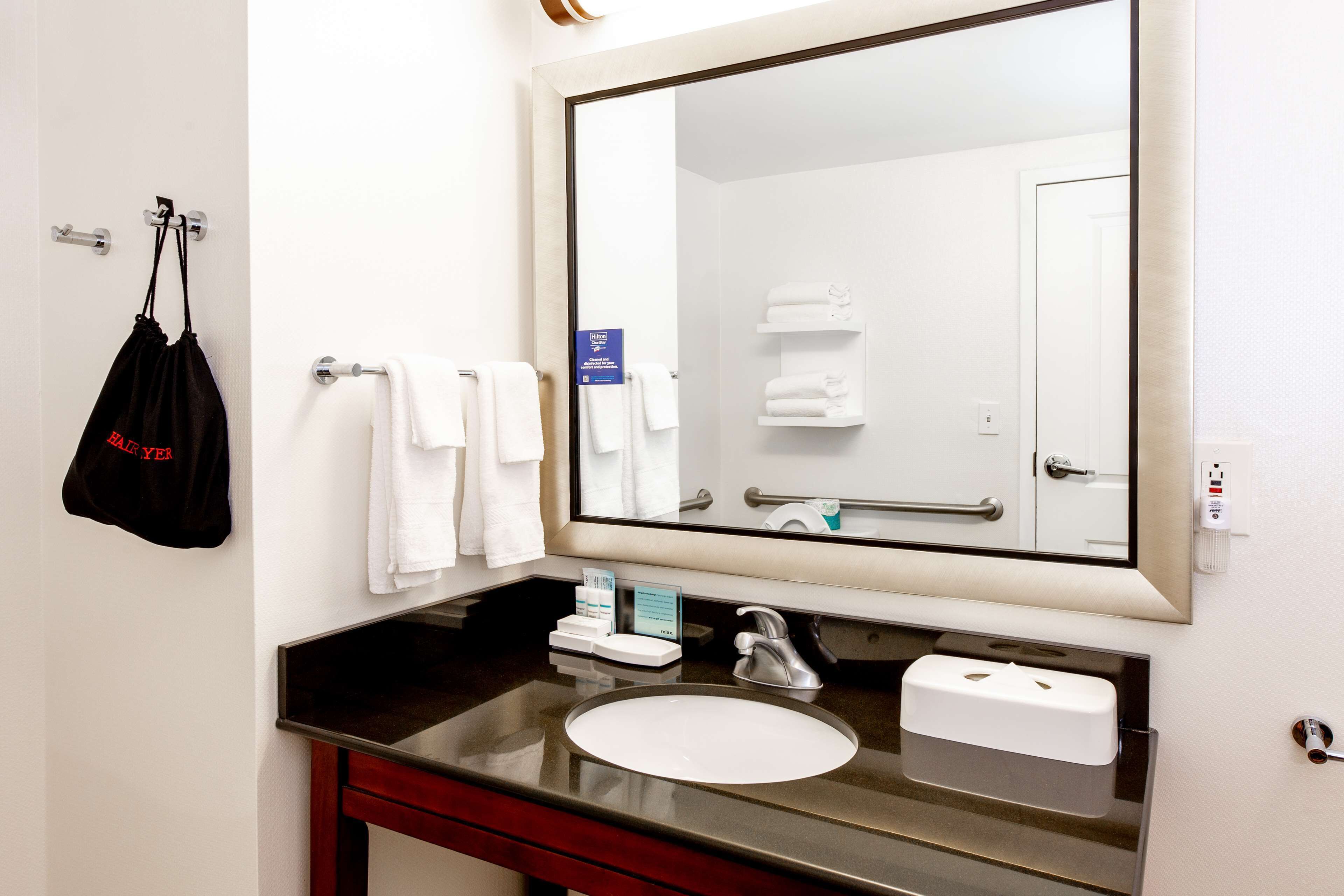 Un baño de hotel con un espejo grande, un lavabo y un perchero para toallas.