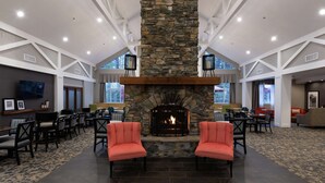 A spacious lobby with a stone fireplace, seating area, and large windows. - Hampton Inn & Suites Raleigh Cary Lenovo Center (Raleigh)
