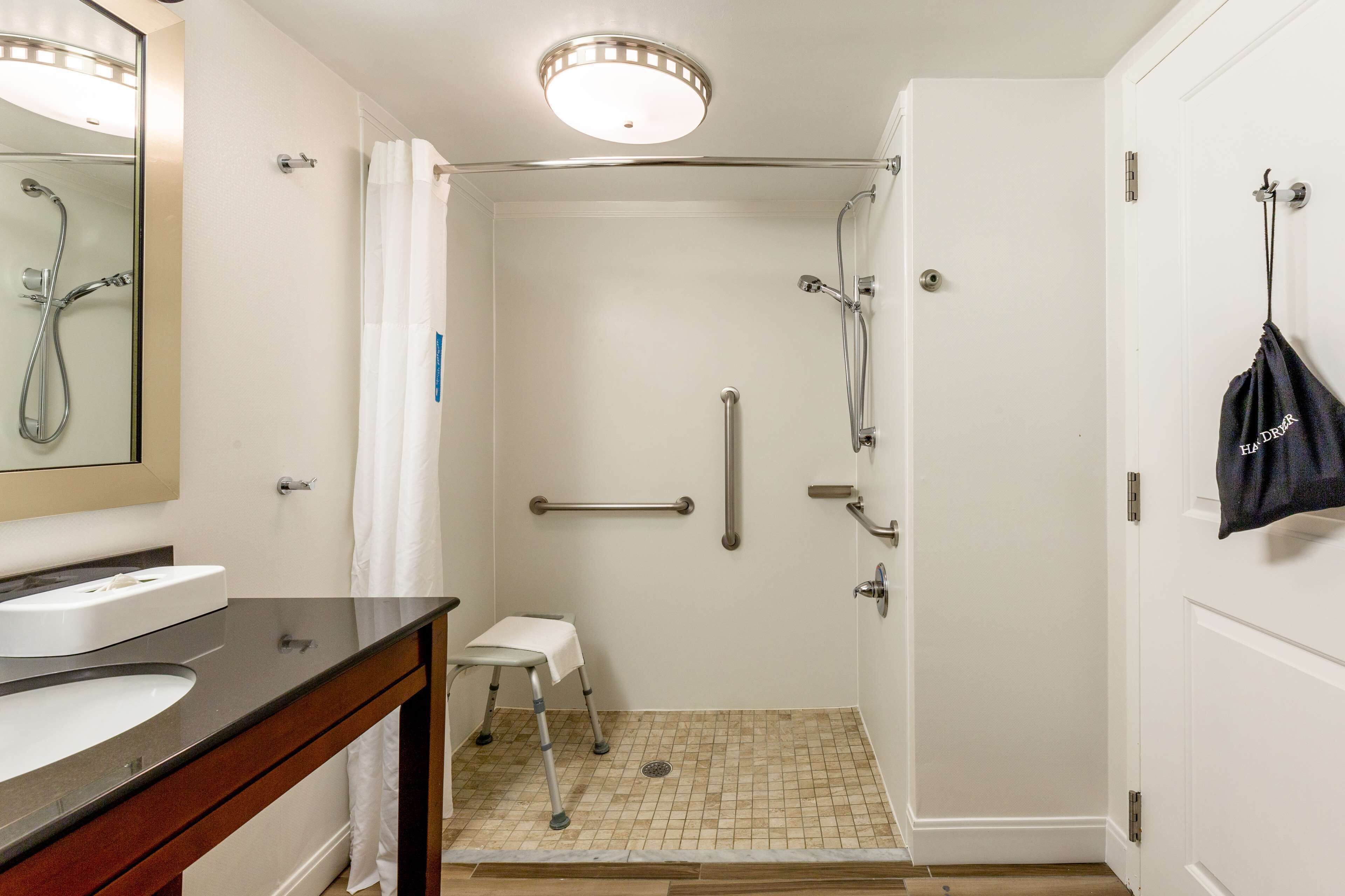 A hotel bathroom with a shower, a sink, and a mirror.
