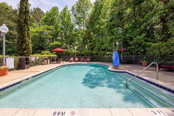 A swimming pool with a 9-meter depth, surrounded by a fence, with lounge chairs and umbrellas.