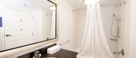 A modern bathroom with a large mirror, a white sink, a bathtub, and a shower.