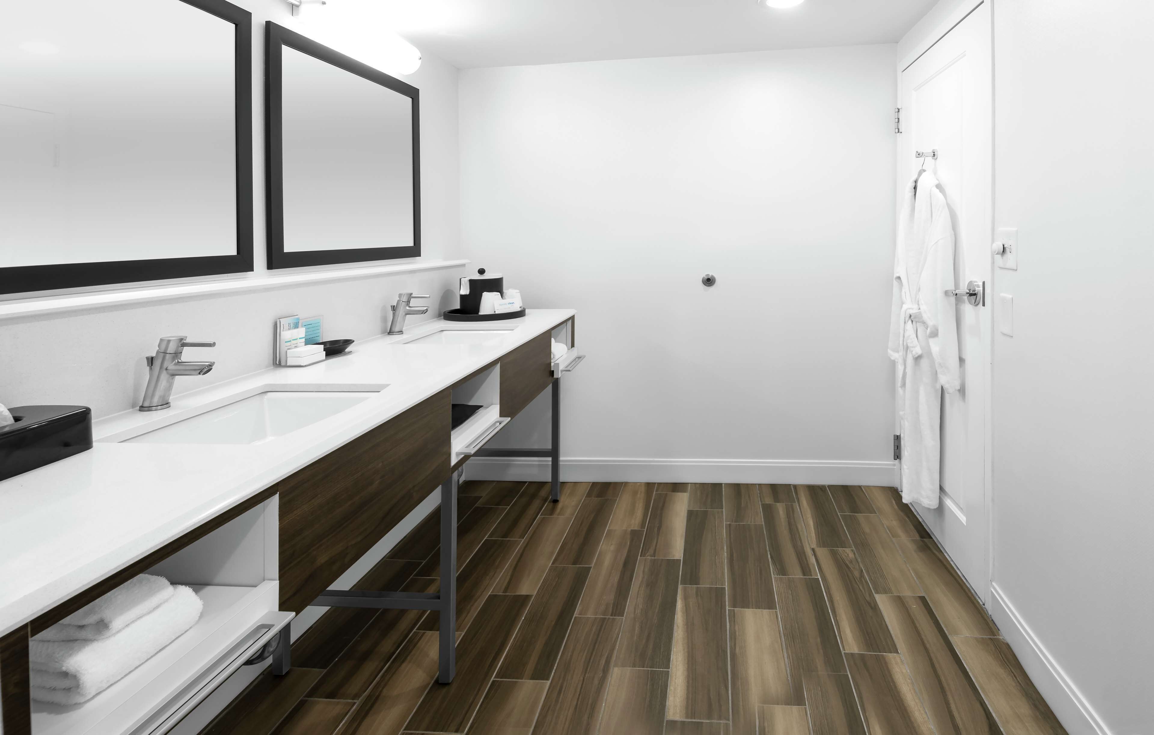 A modern bathroom with two sinks, a mirror, and a shower.