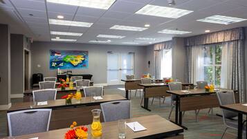 A conference room with tables, chairs, and a large painting on the wall.