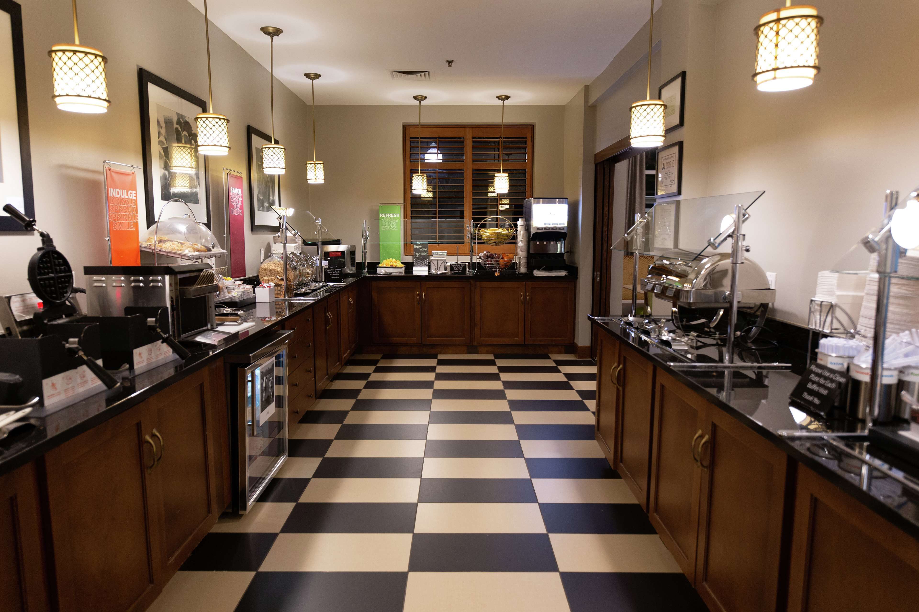 Une cuisine d’hôtel avec un carrelage à motifs, des armoires en bois et divers équipements utilisés pour la préparation et le service des repas.