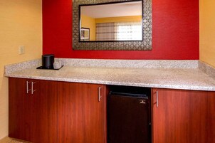 Una cocina con encimera de granito, armarios de madera, lavavajillas negro y un espejo con marco decorativo.