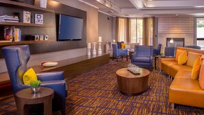 Un moderno hall de hotel con alfombra estampada, sofás de cuero, un televisor de pantalla plana y una chimenea.