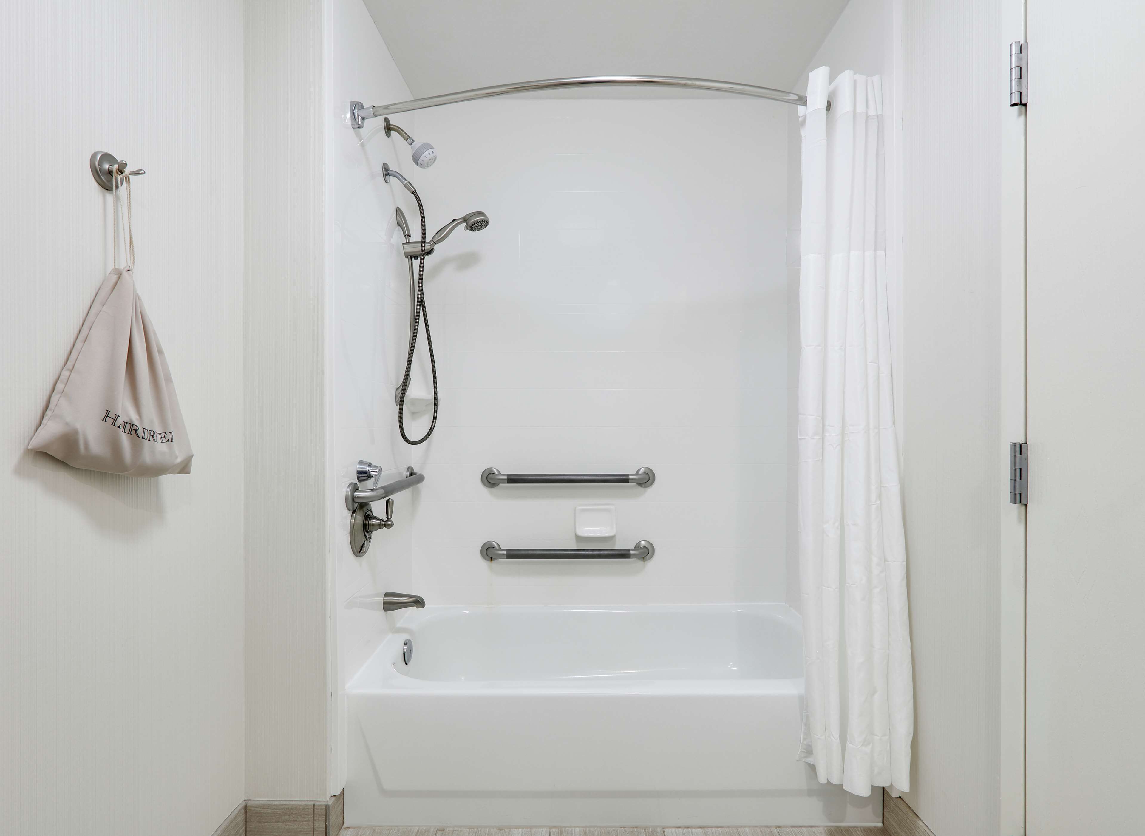 Un baño moderno con bañera, ducha y barras de apoyo.