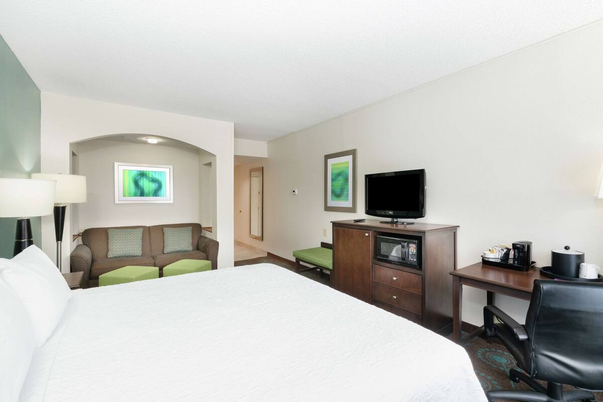 A hotel room with a bed, a desk, a television, a coffee maker, and a sofa.