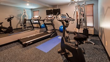 Un gimnasio con cintas de correr, elípticas y pelotas de ejercicio.
